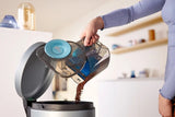 Taghareed Philips 5000 Series bagless vacuum cleaner dustbin being emptied. Blue accents.