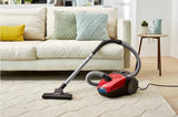 Taghareed Philips 2000 Series bagged vacuum cleaner in red and black, with multi-purpose nozzle on a cream rug.